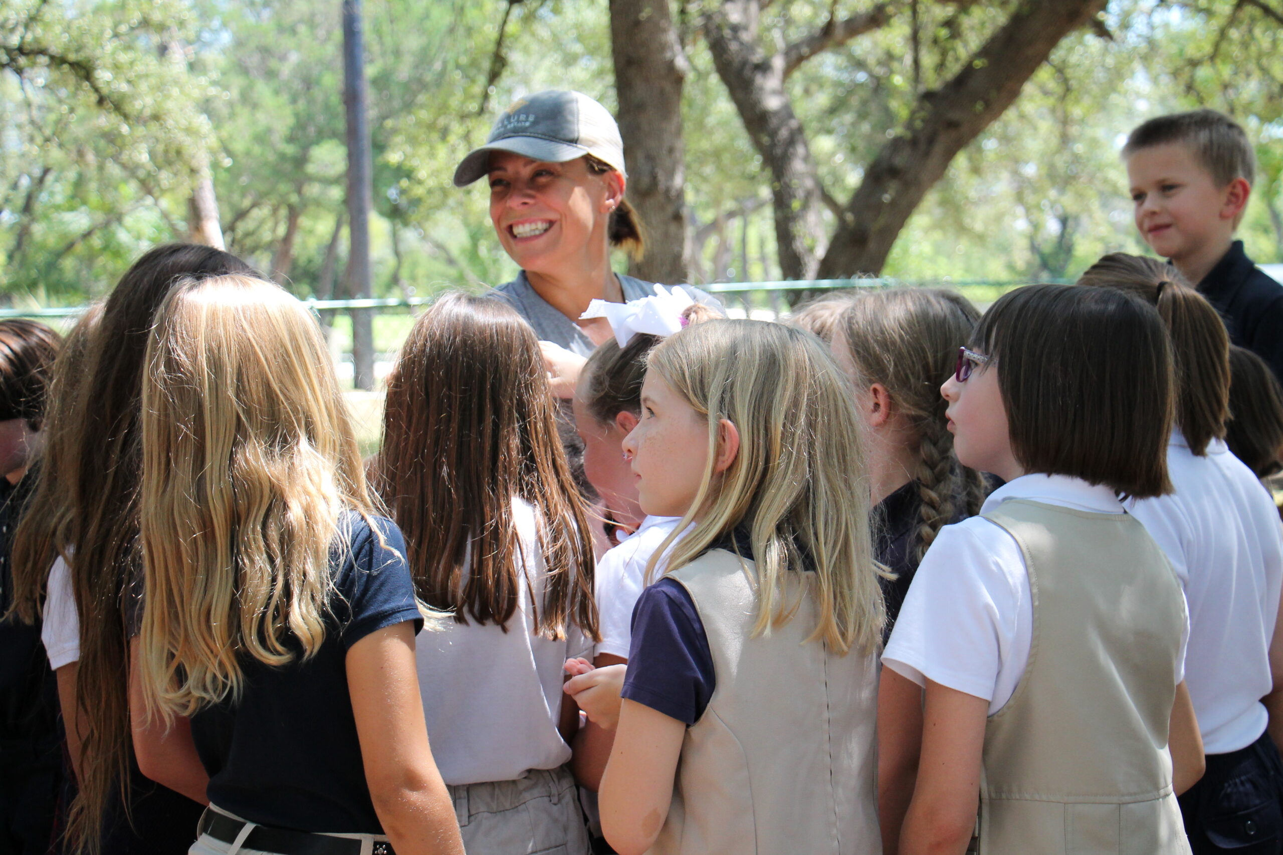 A woman holds a small pig as students gather around to see it.