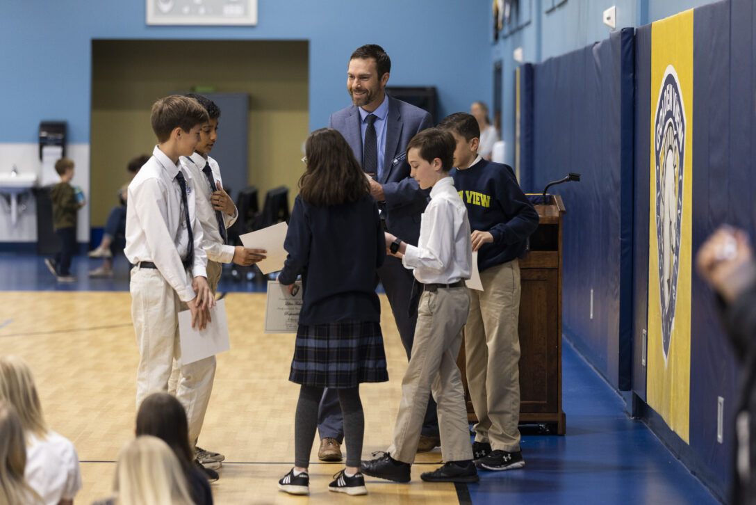 School administrator hands character awards to students.